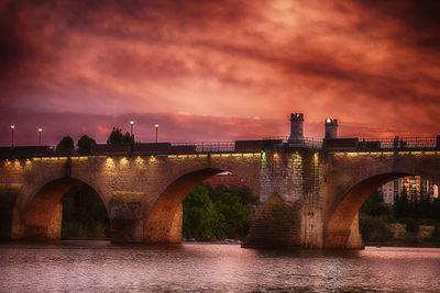 Arch bridge over river against sky at night