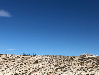 People on arid landscape against clear blue sky