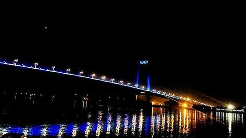 Illuminated bridge over river at night