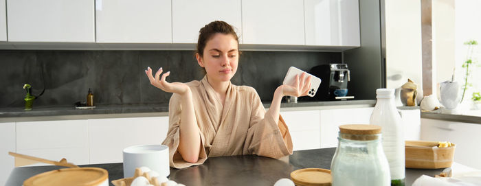 Portrait of young woman sitting in kitchen