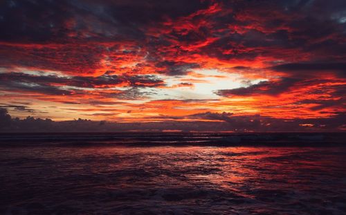 Scenic view of sea against dramatic sky during sunset