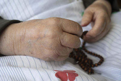 Midsection of woman holding beaded necklace