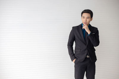 Full length of a young man standing against wall
