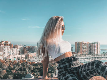 Woman looking at city buildings against sky