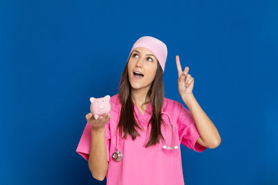 Portrait of young woman standing against pink blue sky