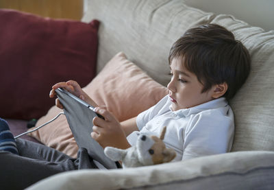 Boy looking away while relaxing on sofa at home