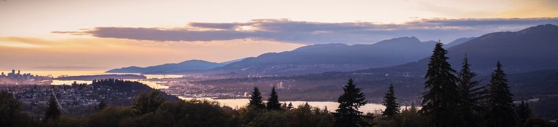 Panoramic view of trees and mountains against sky during sunset