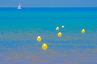 View of balloons in sea against blue sky