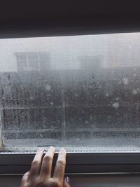 Cropped hand of woman reaching window