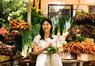 Portrait of smiling young woman standing in market