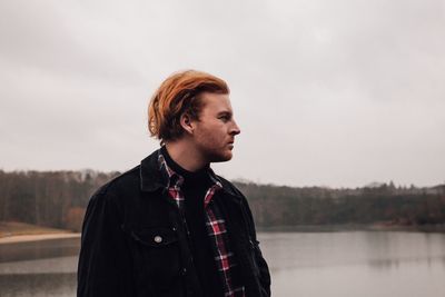 Man looking away while standing against sky