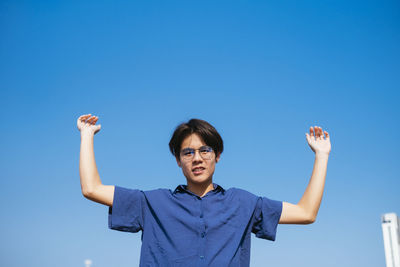 Portrait of smiling man standing against clear blue sky