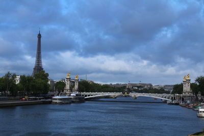 View of city at waterfront against cloudy sky