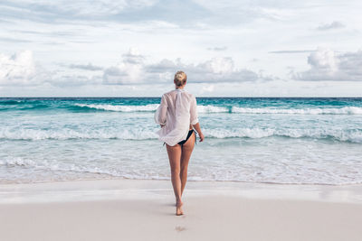 Rear view of woman standing at beach