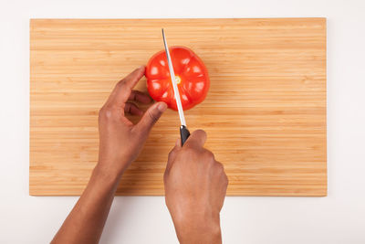 Directly above shot of hand holding strawberry on cutting board