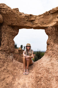 Rear view of woman sitting on rock formations