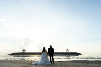 Rear view of women on beach against sky