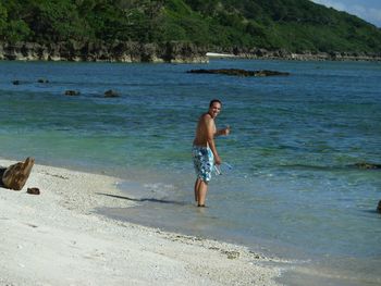 Portrait of man gesturing thumbs up while standing at beach