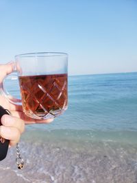 Woman holding ice cream in sea against clear sky