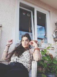 Portrait of woman smoking cigarette while sitting on chair at home