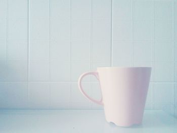 Close up of coffee cup on table against tiled wall