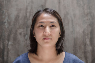 Close-up portrait of a young woman against wall