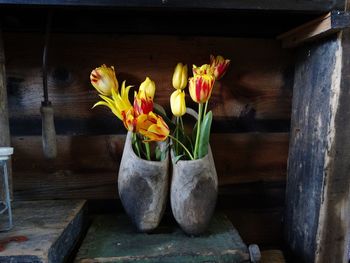 Flower vases with yellow flowers in front of wooden wall