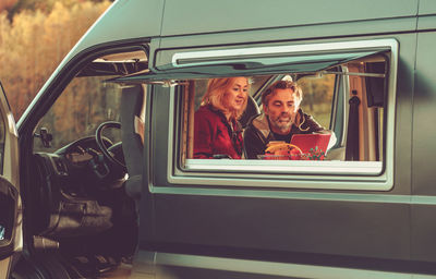 Smiling couple watching movie while sitting in motor home