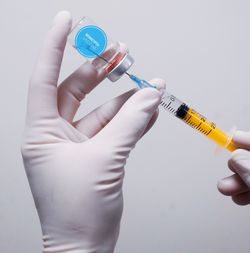 Cropped hand holding syringe against white background