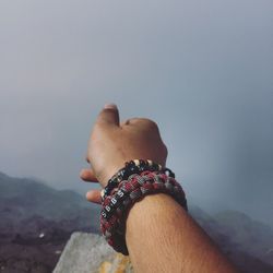 Close-up of man hand on beach against sky