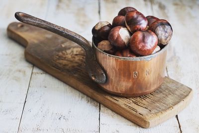 Close-up of chestnuts in container on cutting board over table