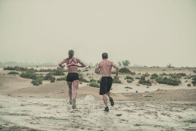 Rear view of man running on beach against clear sky