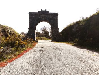 Road leading to built structure against sky