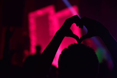 Close-up of silhouette hand on heart shape at night