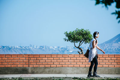 Woman standing on retaining wall against sky