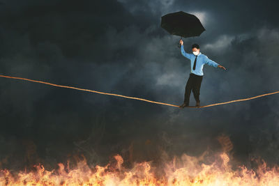 Full length of man holding umbrella against sky