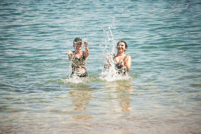 Two women splashing water on the beach 