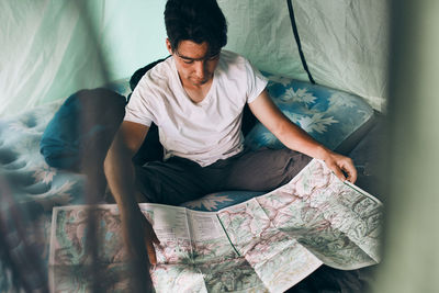 Young man looking at a map of mountain trails planning next trip on summer vacation