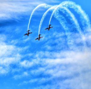 Low angle view of airshow against blue sky