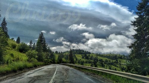 Road amidst trees against sky