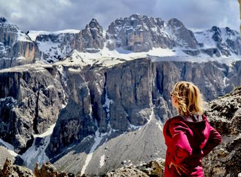 Woman standing on rock against snowcapped mountains