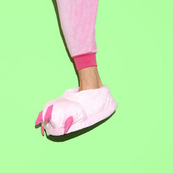 Low section of woman wearing shoes over pink background