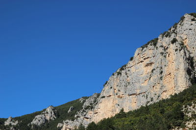 Low angle view of rock formation against clear blue sky