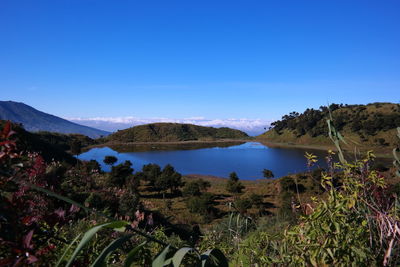 Scenic view of sea and mountains against clear blue sky