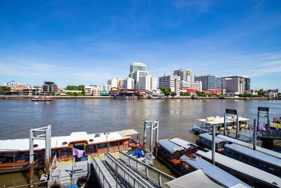 City by river and buildings against sky