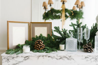 Christmas decor in home decoration photo frame, spruce branches, glasses, candles and cones