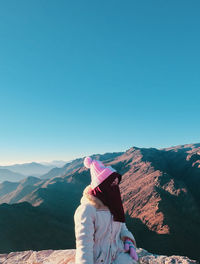 Rear view of woman looking at mountain against clear sky