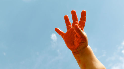 Low angle view of cropped hand against clear sky