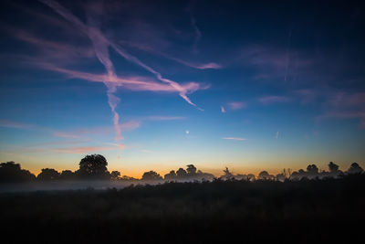 View of foggy field with clouds in blue sky at dusk