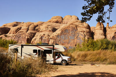 An rv parked in front of a red rock wall in moab, utah.